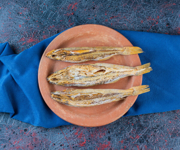 Salty dried fish isolated on a clay plate on a dark background . High quality photo